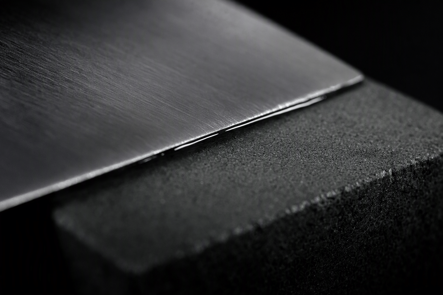 A blade edge resting on a wet whetstone